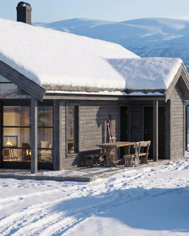 Vinterhytte i snølandskap med store vinduer og fjellutsikt, ideell for koselige vinteropplevelser.